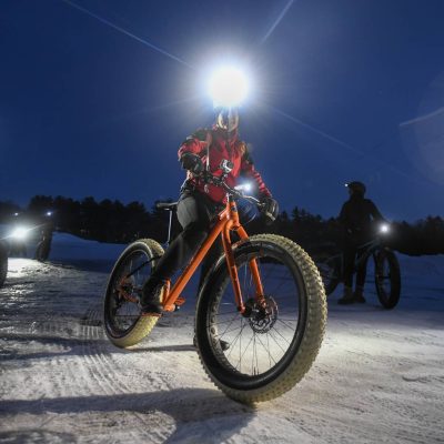 Related Article: Winter getaways for trail lovers | woman riding a fatbike on a winter night at the lambo zip trail in manitowoc wisconsin