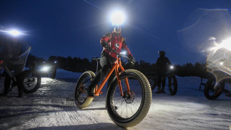 Article: Winter getaways for trail lovers | woman riding a fatbike on a winter night at the lambo zip trail in manitowoc wisconsin