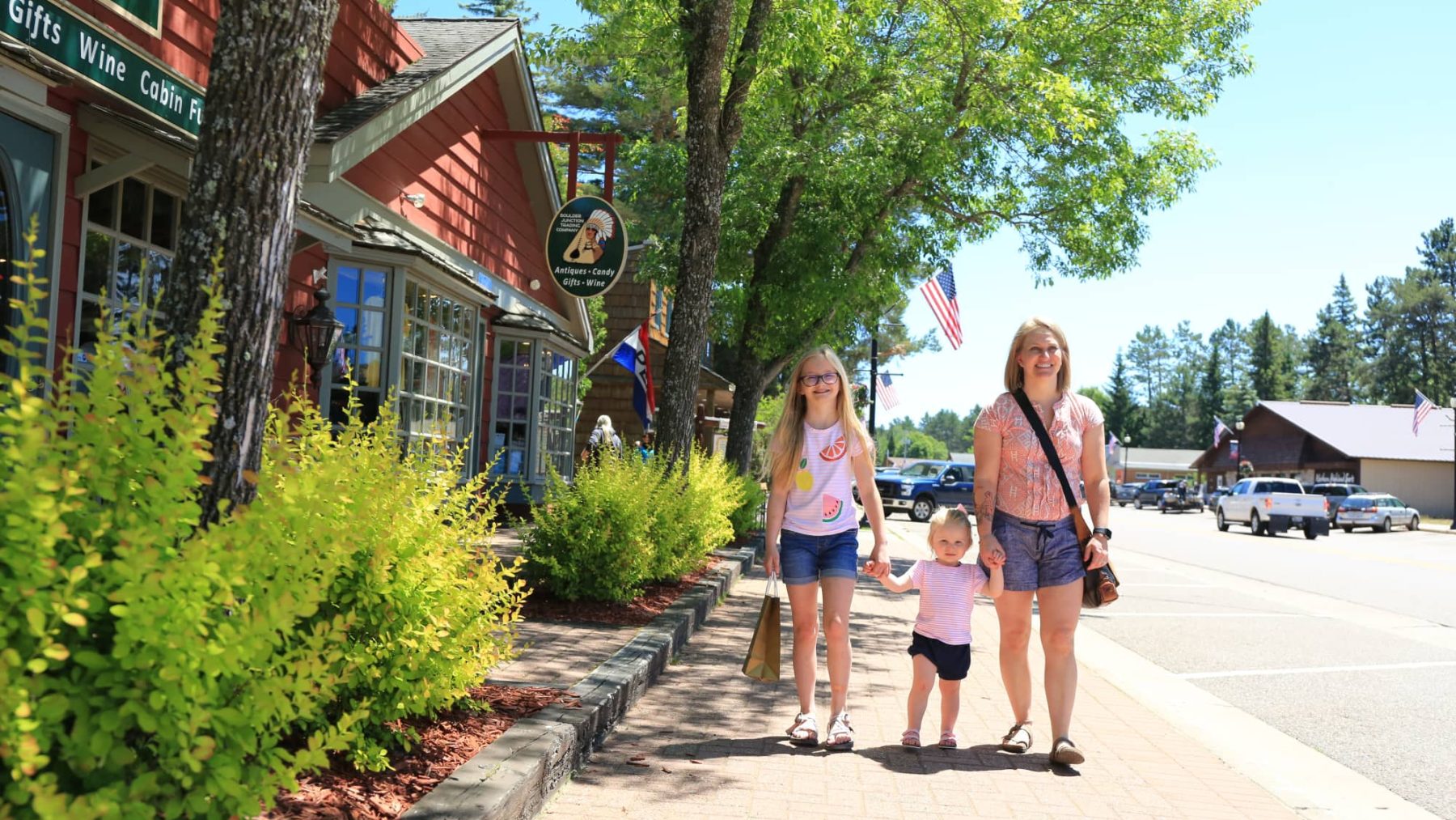 Article: Step into these charming sidewalk shopping destinations | mother and daughters walking on Main Street in downtown Boulder Junction Wisconsin