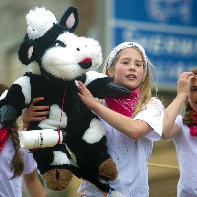 Related Article: What you need to know about Dairyfest | girls in parade holding stuffed cow at Dairyfest in Marshfield, WI