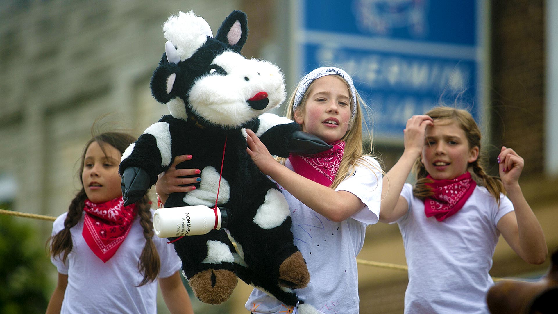 girls in parade holding stuffed cow at Dairyfest in Marshfield, WI