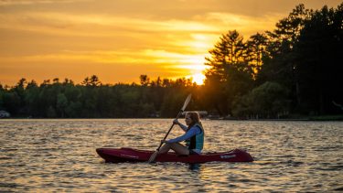 Article: Where to canoe & kayak in Wisconsin | woman kayaking at sunset on otter lake vilas county wisconsin