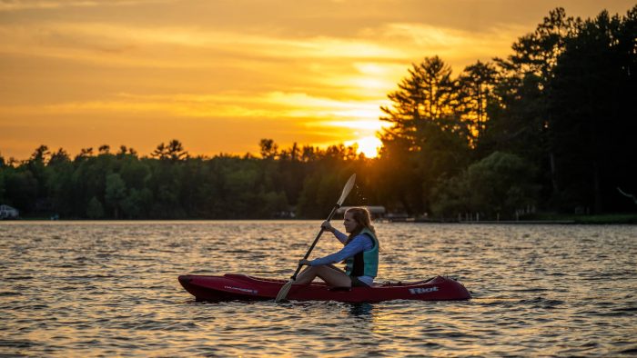 Article: Where to canoe & kayak in Wisconsin | woman kayaking at sunset on otter lake vilas county wisconsin