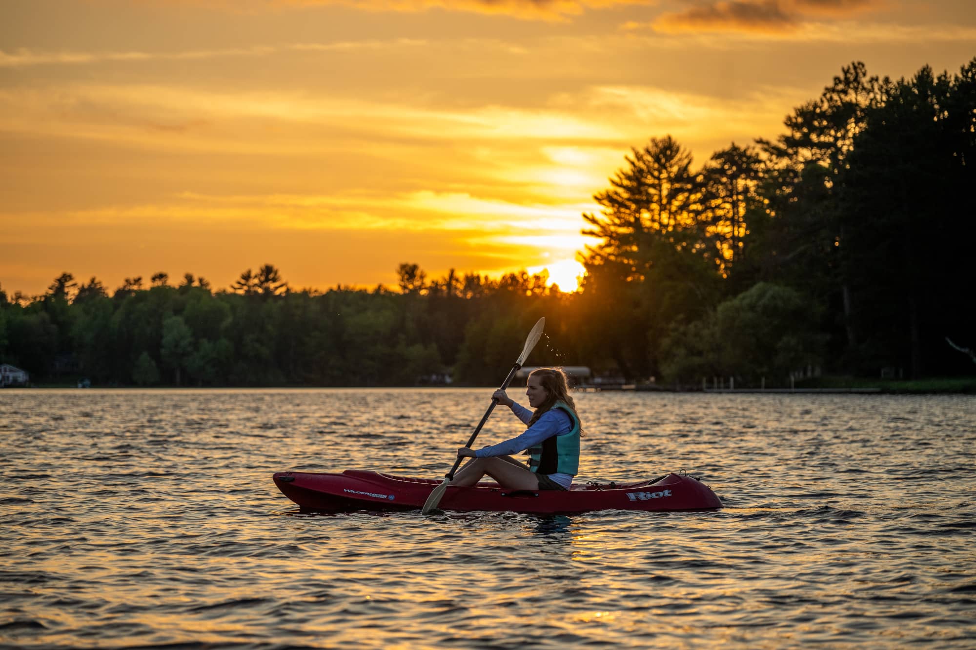 woman kayaking at sunset on otter lake vilas county wisconsin