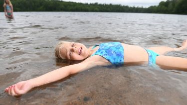 Article: Where to cool off in Wisconsin this summer | Girl swimming at Nichols Beach in Boulder Junction WI