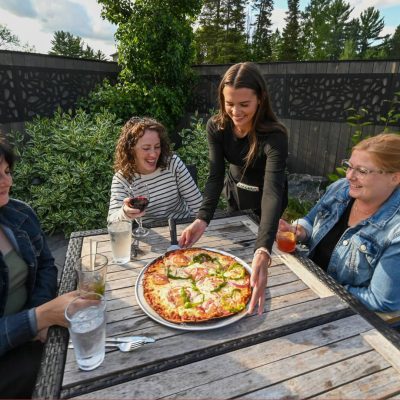 Related Article: Discover great dining options in Oneida County | Women eating pizza at Claytons’ 1881 Room Three Lakes Oneida County WI